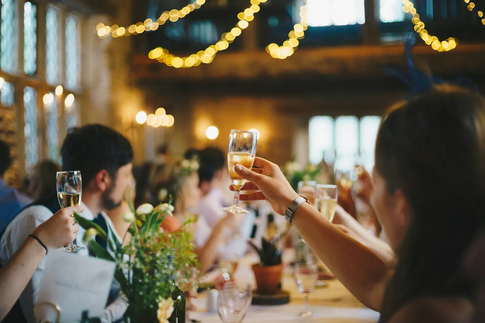 Guests raising a toast at a celebration under string lights