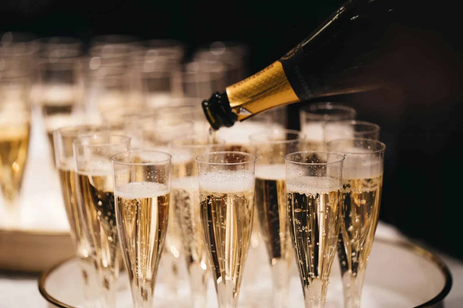 Champagne being poured into rows of glasses